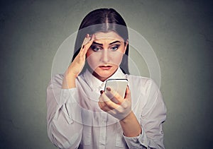 Upset shocked serious woman looking at her mobile phone.