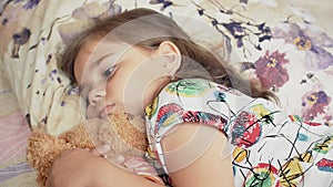 Upset sick child girl lying on a bed