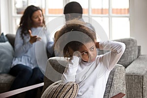 Upset small black girl cover ears avoiding family conflict