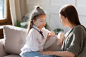 Upset small schoolgirl having trustful conversation with mother.