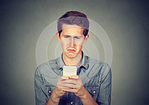 Upset stressed man holding cellphone disgusted with message received