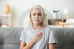 Upset stressed mature older woman feeling heartache touching che