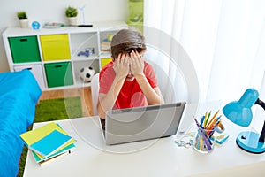 Upset student boy with laptop computer at home