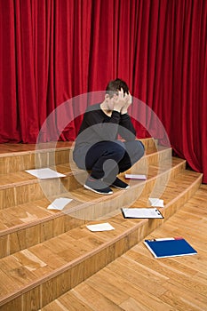 An upset student sits near the stage of the theater.