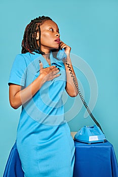 Upset surprised excited african american woman secretary calls on the phone. blue background