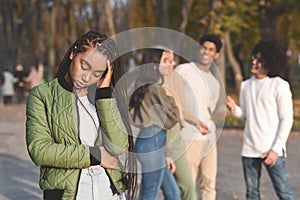 Upset Teen Black Girl With Friends Gossiping In Background