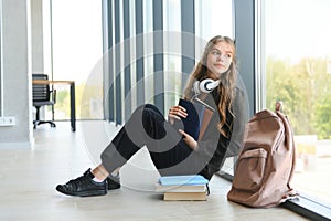 Upset teen girl sit on floor sadly look out window worried about teenage problem at school and communication with parent