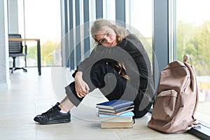 Upset teen girl sit on floor sadly look out window worried about teenage problem at school and communication with parent