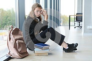 Upset teen girl sit on floor sadly look out window worried about teenage problem at school and communication with parent