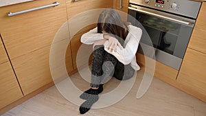 Upset teenage girl feeling lonely and misunderstood crying on kitchen. Mental problems and depression of teens