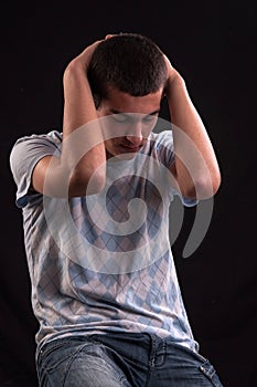 Upset teenager with head in hands wincing from stress, anguish o