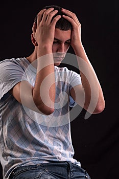 Upset teenager with head in hands wincing from stress, anguish o photo