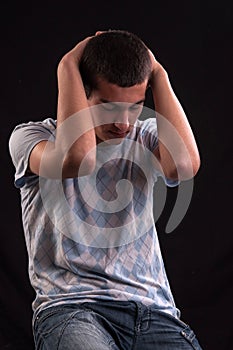 Upset teenager with head in hands wincing from stress, anguish o photo