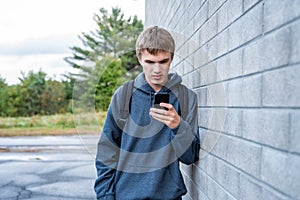 Upset teenager looking at his cellphone.