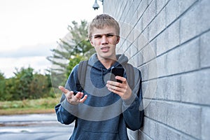 Upset teenager looking at his cellphone.