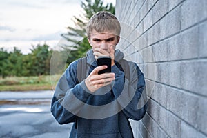 Upset teenager looking at his cellphone.