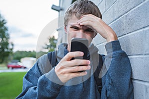 Upset teenager looking at his cellphone.