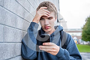 Upset teenager looking at his cellphone.