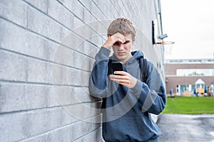 Upset teenager looking at his cellphone.