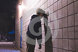 Upset teenager standing in an alleyway.