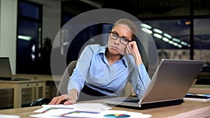 Upset and tired business woman sitting at office late at night, troubles at work