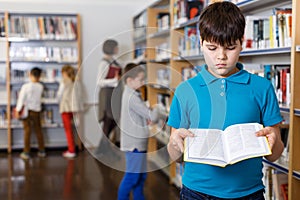 Upset tween boy browsing book