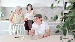 Upset and unhappy young son-in-law sitting in the kitchen separately, family conflict