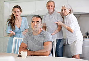 Upset and unhappy young son-in-law sitting in kitchen separately, family conflict