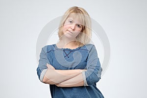 Upset unsatisfied blonde woman standing with arms folded