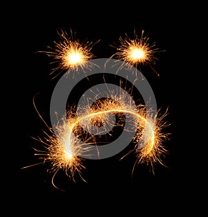 Upset weird sad smiley drawn with sparkles on black background