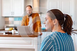 Upset wife or Girlfriend looking towards husband after conflict argument While man use laptop.Young married couple after