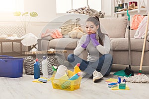 Upset woman cleaning house with lots of tools