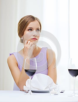 Upset woman with glass of whine waiting for date