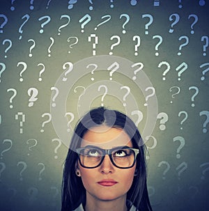 Upset woman with glasses looking up question marks above head
