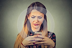 Upset woman holding cellphone. Sad looking girl texting on smartphone