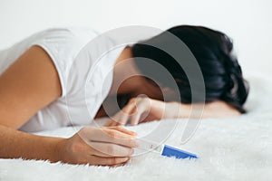 Upset woman lie sad in the bed with negative pregnancy test