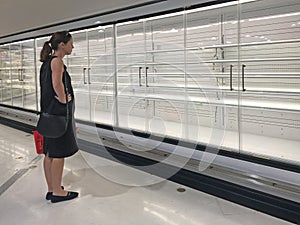 Upset woman looking at empty commercial fridges