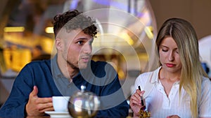 Upset woman and man talking in cafe about problem in relationships. Couple sitting at table in cafe together