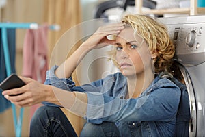 Upset woman posing next to washing machine