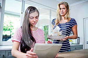 Upset woman showing dirty dishes to friend