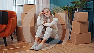 Upset woman sitting on floor near cardboard boxes with stuff, long relocation, bankruptcy, bank debt