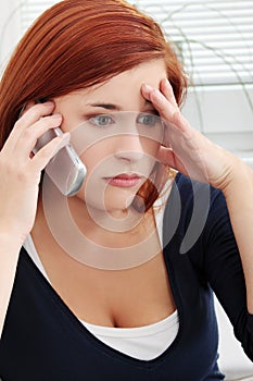 Upset and worried young woman talking by phone photo