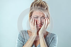Upset young blond woman crying with big tears expressing sorrow
