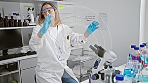 Upset young blonde woman scientist struggles with research problem, working tirelessly on analysis using microscope in lab