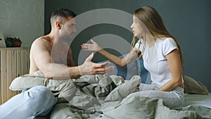 Upset young couple in sitting in bed upset and argue each other