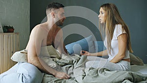 Upset young couple in sitting in bed upset and argue each other