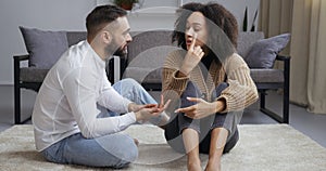 Upset young family couple african american girl black wife sitting on floor holding her head with hands worried about