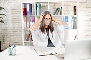 Upset young female doctor looking at laptop