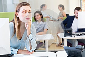 Upset young female foreground in busy open plan office indoor