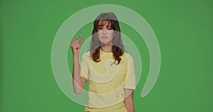 Upset young girl look at hand showing with pity little size gesture, shrug and sigh on chromakey green studio background